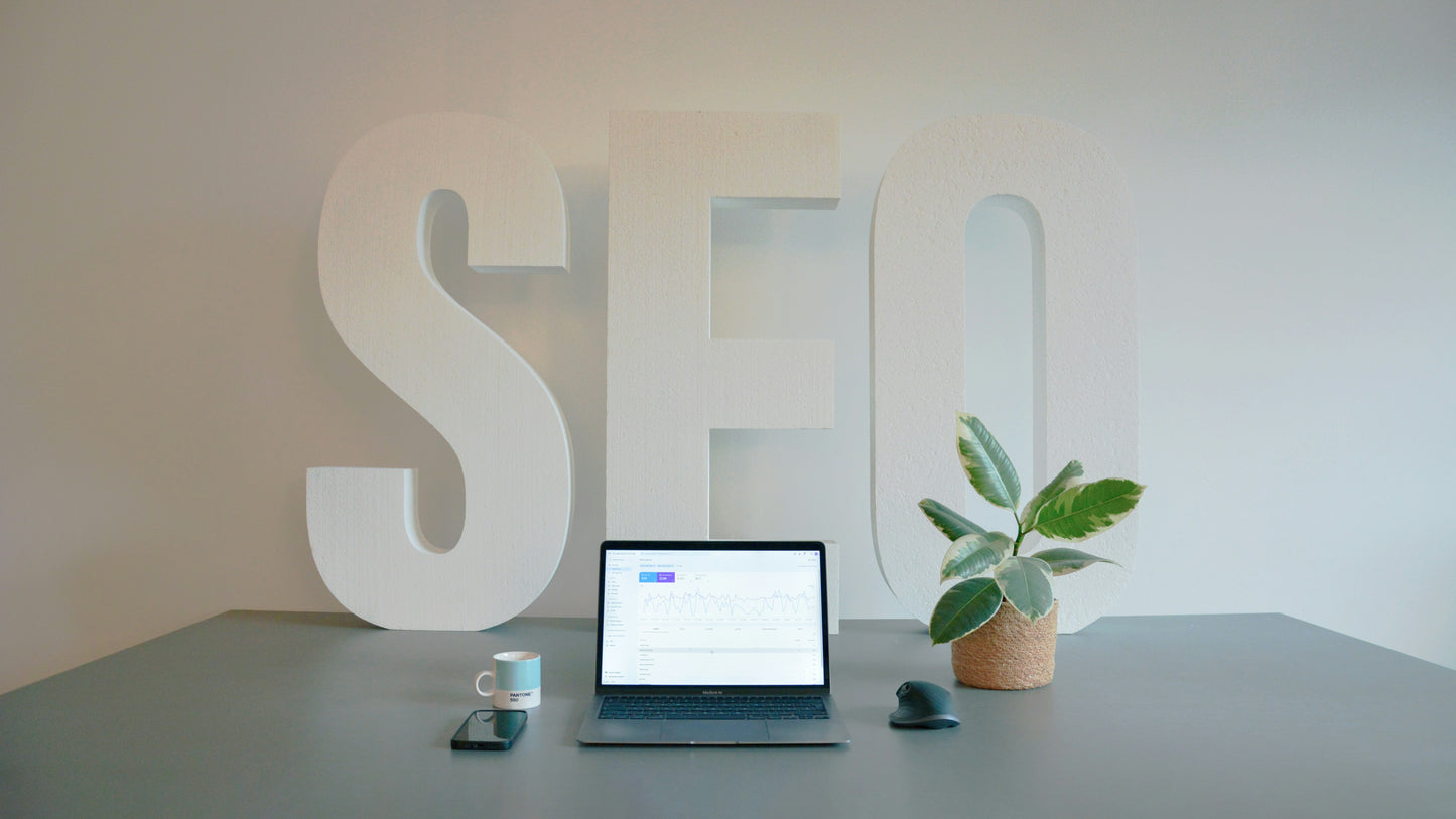 Laptop on a desk with 'SEO' letters in the background