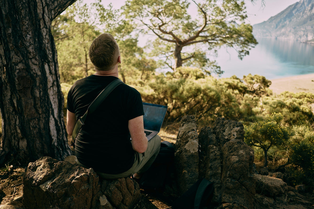 person looking into the lake from hill while on laptop