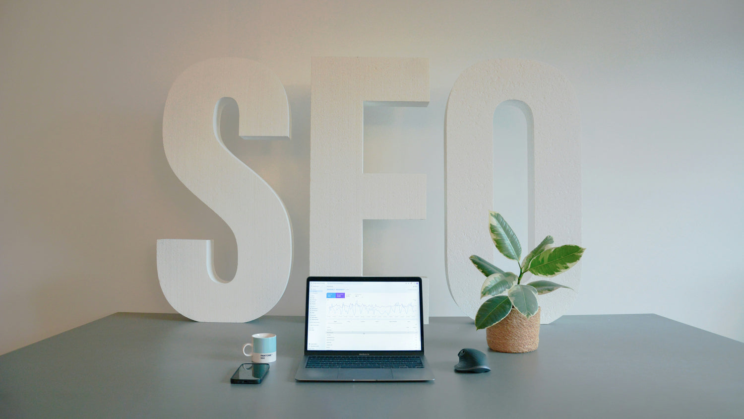 Laptop on a desk with 'SEO' letters in the background